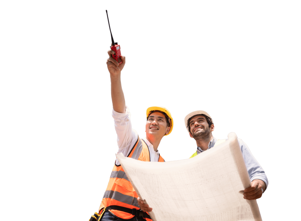 Two construction workers wearing hard hats and reflective vests. One holds a radio and points upwards, while the other holds a large blueprint. They appear to be discussing a project.